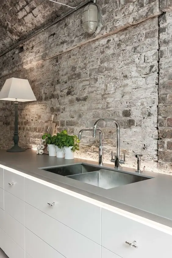 white modern kitchen with rough brick wall