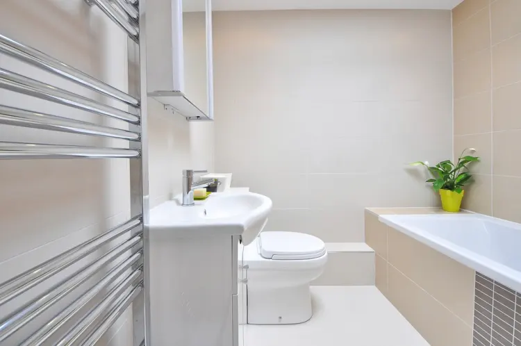 Small bright bathroom with a chrome ladder heated towel rail on the wall