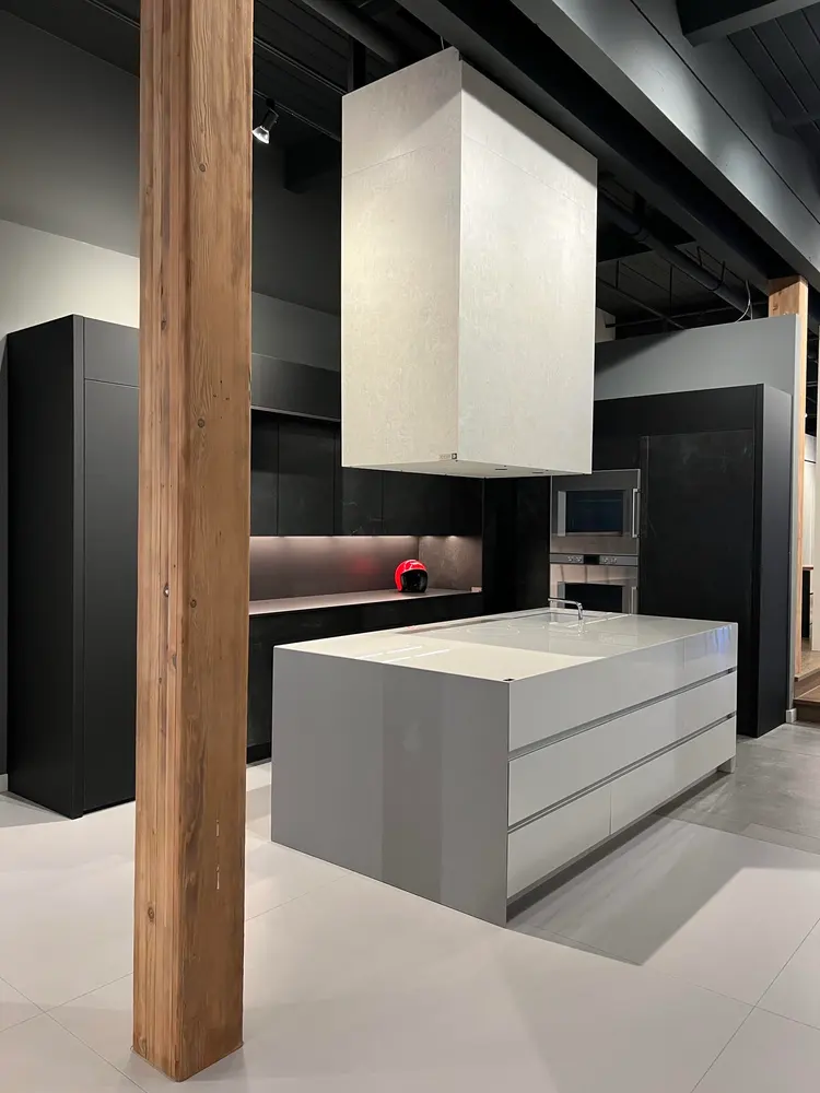 A dark kitchen with a white sintered stone island and stone hood wrap